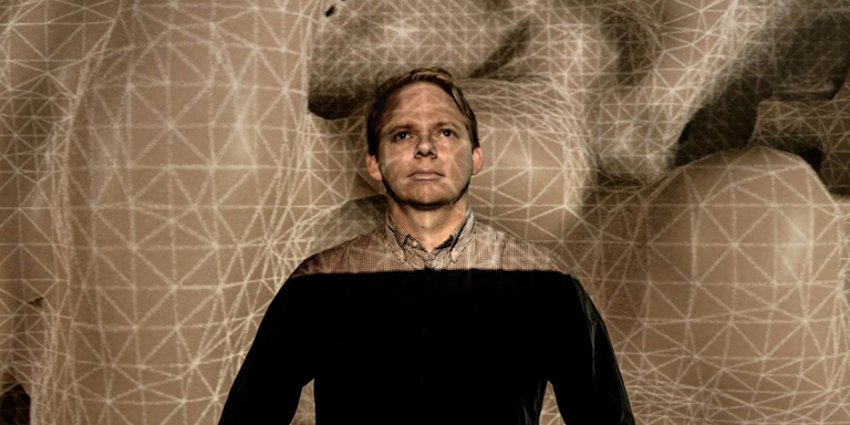 Baden Pailthorpe standing in front of his work Clanger, a projected topology of gridded land forms