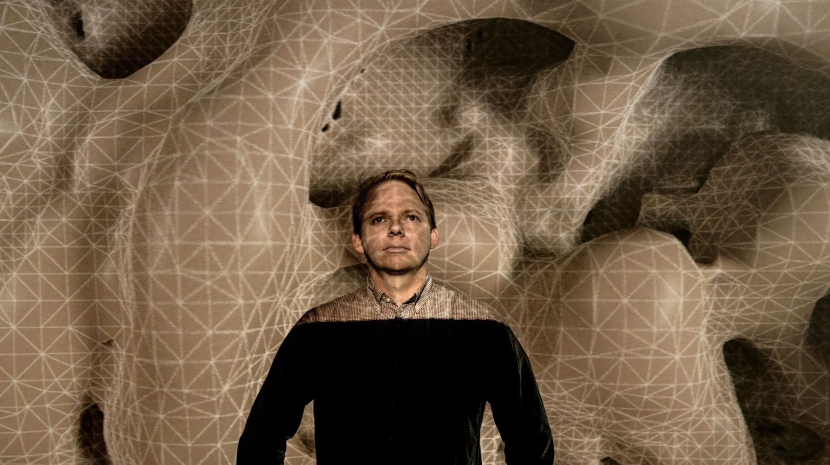 Baden Pailthorpe standing in front of his work Clanger, a projected topology of gridded land forms